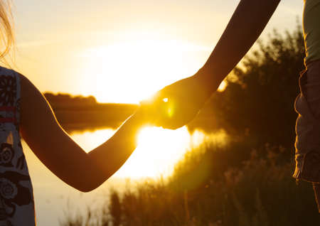 Hands of holding each other on lake and sunの写真素材