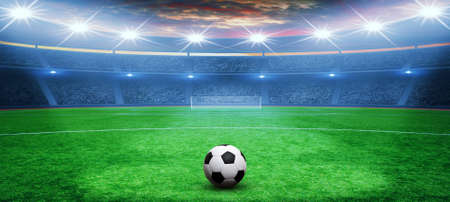 Soccer ball on green stadium, arena in night illuminated bright spotlightsの写真素材