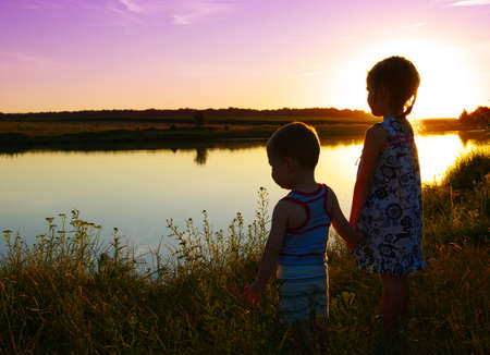 little boy and girl in the field looking the lake
