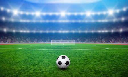 Soccer ball on green stadium, arena in night illuminated bright spotlightsの写真素材