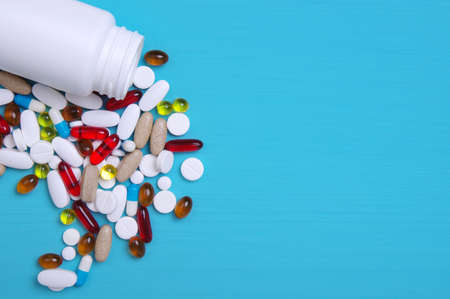 Pills, tablets and capsules on wooden blue background