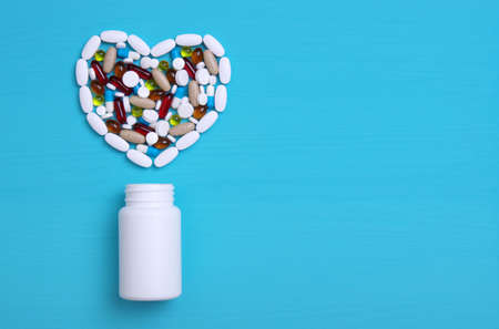 Pharmaceutical medicine pills, tablets and capsules in the shape of a heart on a blue background