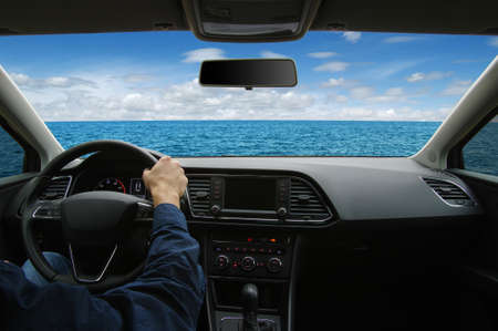 The man inside the car is driving along the road