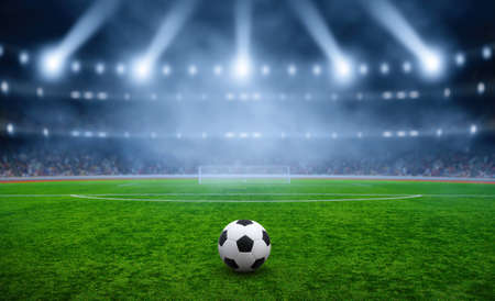 Soccer ball on green stadium, arena in night illuminated bright spotlightsの写真素材