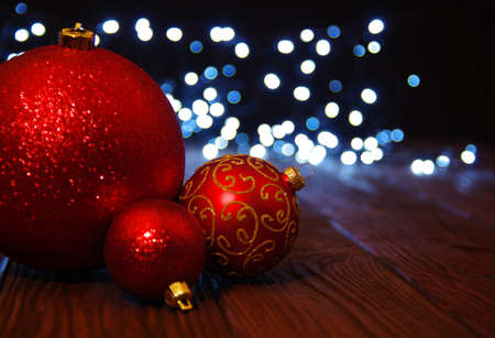 Red Christmas balls on a wooden table and lights  background.の写真素材