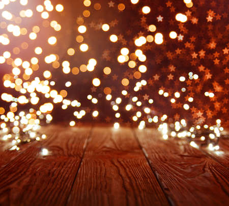 Background with golden bokeh and a empty wooden table with christmas lightの写真素材