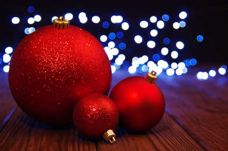 Red Christmas balls on a wooden table and lights  background.の写真素材