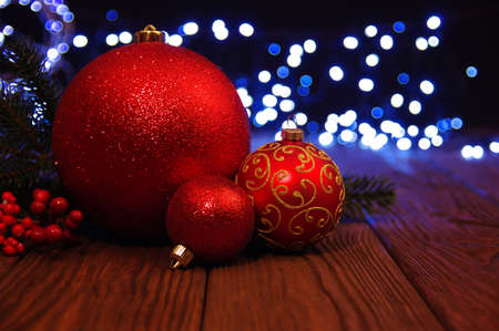 Red Christmas balls on a wooden table and lights  background.の写真素材