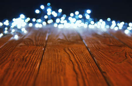 Christmas Bokeh background with rustic empty wooden tableの写真素材