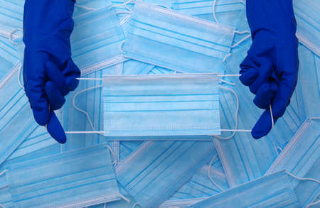 Doctor hand wear blue gloves holds medical mask on blue background.の写真素材