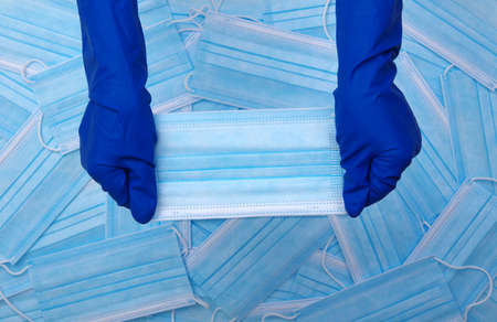 Doctor hand wear blue gloves holds medical mask on blue background .の写真素材
