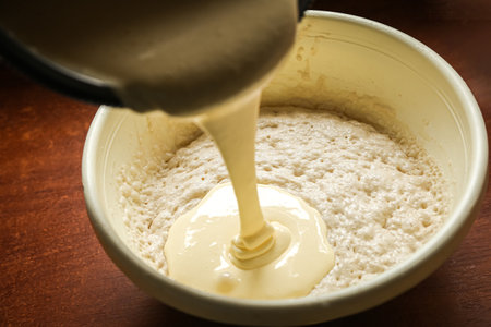 the process of cooking cooking dough in a yellow toe on a dark wooden table.