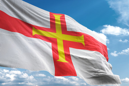 Guernsey flag waving blue sky background 3D illustrationの写真素材