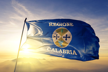 Calabria region of Italy flag textile cloth fabric waving on the top sunrise mist fogの写真素材