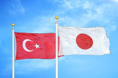 Turkey and Japan two flags on flagpoles and blue cloudy sky backgroundの写真素材