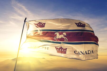 Guelph of Ontario of Canada flag textile cloth fabric waving on the top sunrise mist fogの写真素材
