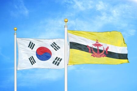 South Korea and Brunei Darussalam two flags on flagpoles and blue cloudy sky backgroundの写真素材