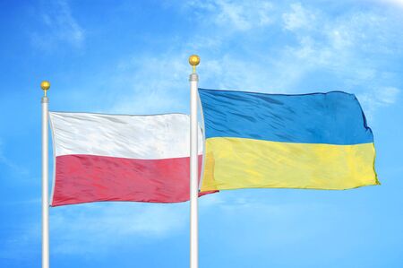 Poland and Ukraine two flags on flagpoles and blue cloudy sky backgroundの写真素材