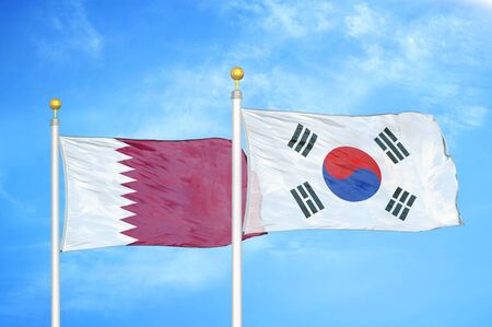 Qatar and South Korea two flags on flagpoles and blue cloudy sky backgroundの写真素材