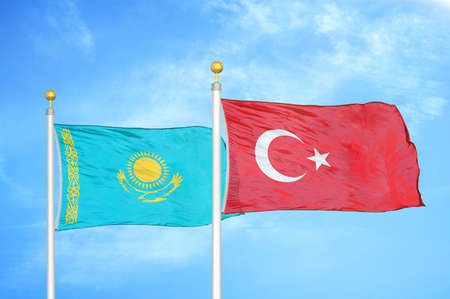 Kazakhstan and Turkey two flags on flagpoles and blue cloudy sky backgroundの写真素材
