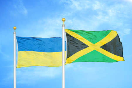 Ukraine and Jamaica two flags on flagpoles and blue cloudy sky backgroundの写真素材