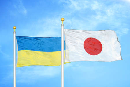 Ukraine and Japan two flags on flagpoles and blue cloudy sky backgroundの写真素材