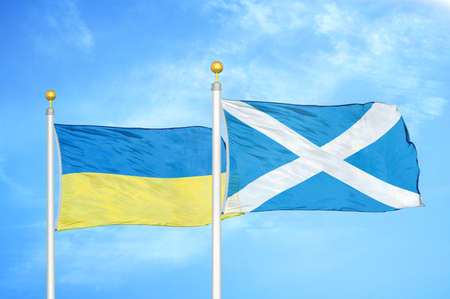 Ukraine and Scotland two flags on flagpoles and blue cloudy sky backgroundの写真素材