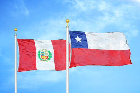 Peru and Chile two flags on flagpoles and blue cloudy sky backgroundの写真素材