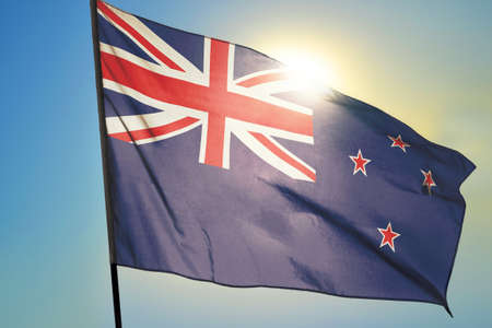 New Zealand flag waving on the wind in front of sunの写真素材
