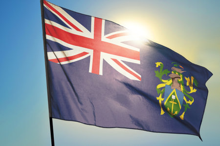 Pitcairn Islands flag waving on the wind in front of sunの写真素材