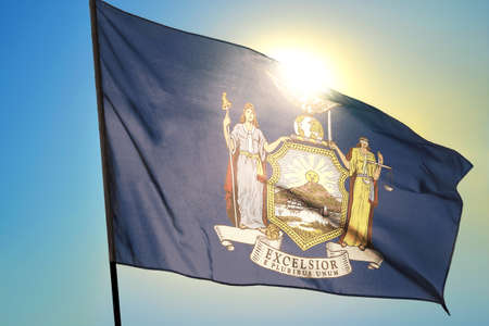 New York state of United States flag waving on the wind in front of sunの写真素材