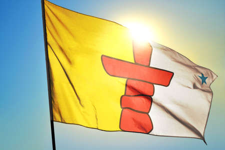 Nunavut province of Canada flag waving on the wind in front of sunの写真素材
