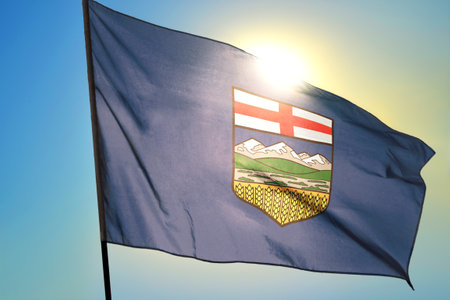 Alberta province of Canada flag waving on the wind in front of sunの写真素材