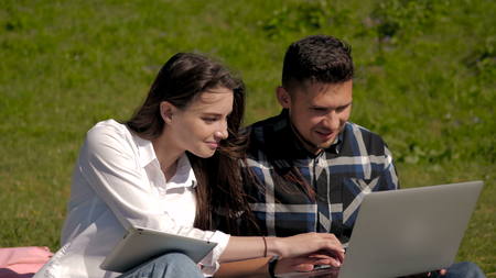 College Students Using Laptop And Tablet PC On Campus Lawn, Outdoor Study Concept, 4Kの写真素材