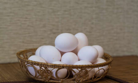 white eggs stacked in a wicker basket and laid on the table