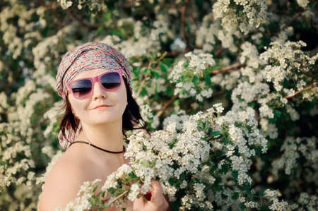 against a blossoming apple-tree there is a woman in sunglassesの写真素材