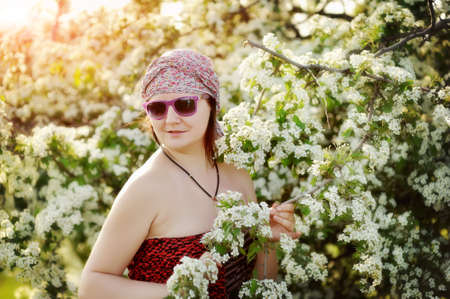 against a blossoming apple-tree there is a woman in sunglassesの写真素材
