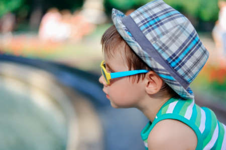 the boy in sunglasses and a cap looks in a distanceの写真素材