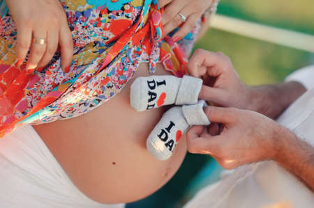 stomach of the pregnant woman and small children s socks