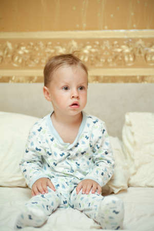 in a bed the woken-up boy in a pajamas sitsの写真素材