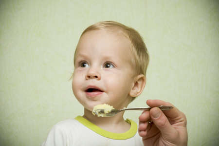 the nice little boy feed with porridge a spoonの写真素材