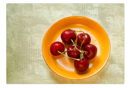 in a yellow plate the ripe red cherry liesの写真素材