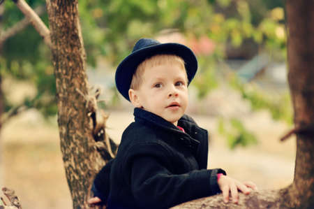 the boy in the autumn wood in a hat and a coat among treesの写真素材