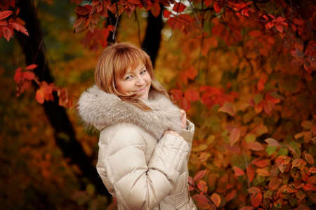 the woman in a white coat poses in the autumn woodの写真素材