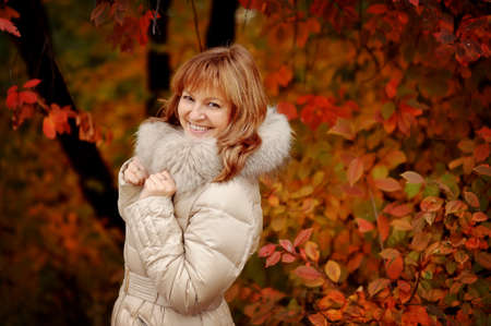 the woman in a white coat poses in the autumn woodの写真素材