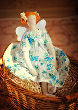 the doll angel with red hair sits in a basketの写真素材