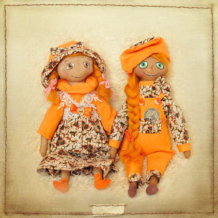 two dolls of handwork in orange suitsの写真素材