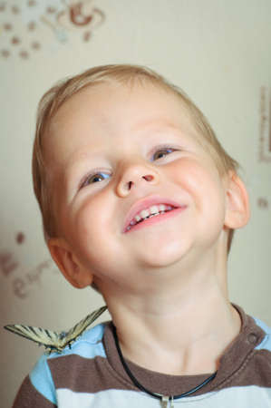 portrait of the boy in a striped vest with a big butterfly on a shoulderの写真素材