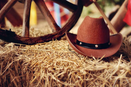 on a haystack the brown cowboy s hat and a wooden wheel liesの写真素材