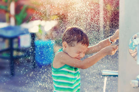 boy having fun with pool fountain shot during summer timeの写真素材